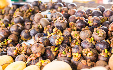 Fresh mangosteen for sale at an outdoor market.