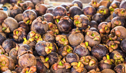 Fresh mangosteen for sale at an outdoor market.