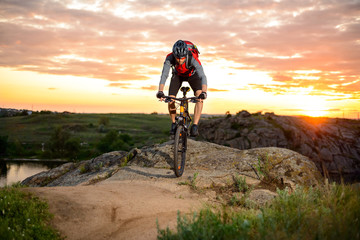 Fototapeta premium Cyclist Riding the Bike on the Mountain Rocky Trail at Sunset