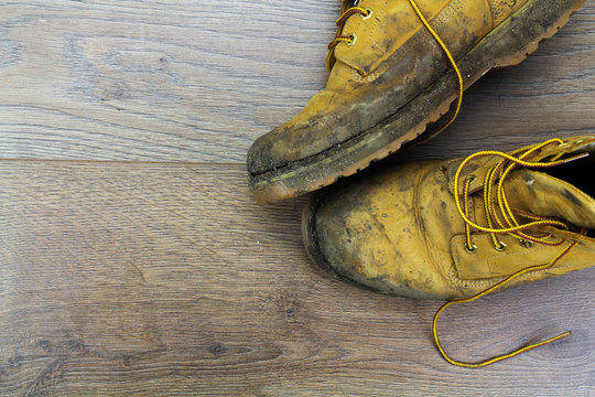 Muddy work boots on a wooden floor