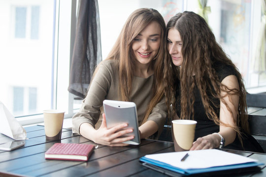 Portrait of young beautiful women looking at tablet screen in ca