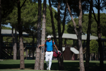 Obraz premium golf player walking and carrying bag