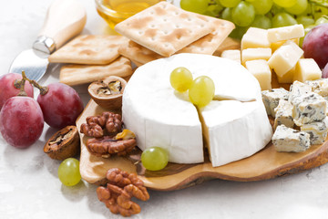 camembert, grapes and crackers on a white table, closeup