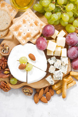 camembert, grapes and snacks on a white background, top view