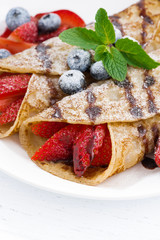 crepes with fresh berries and chocolate sauce, vertical, closeup