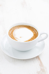cup of cappuccino on a white wooden table, vertical