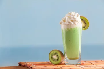 Foto op Plexiglas Milkshake Kiwi smoothie set with sliced kiwi with sea on background. Cocktail made with kiwi and cream. Milkshake with fresh kiwi