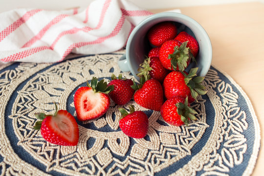Fresh juicy strawberries in old rusty mug. Rustic wooden background with plaid patterned napkin and vintage towel.