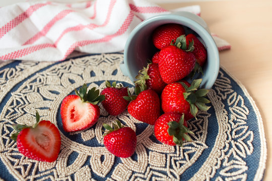 Fresh juicy strawberries in old rusty mug. Rustic wooden background with plaid patterned napkin and vintage towel.