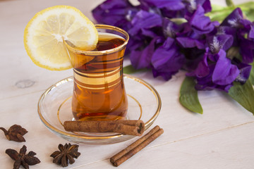 Cup of black tea and blue iris flowers on a light background