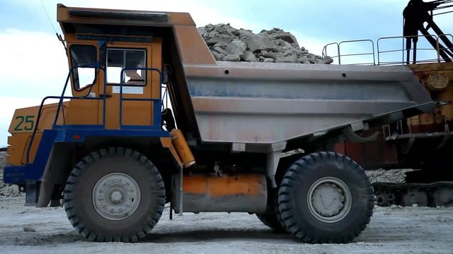 Heavy mining dump trucks driving along the opencast