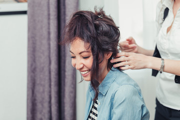 Fototapeta premium A model gets her hair cut and styled by a hipster hair stylist