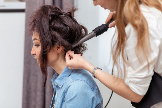Professional hairdresser doing hairstyle to young woman