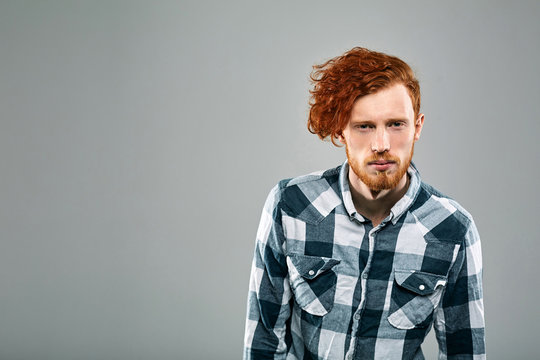 Red Hair Models. Bearded Man. Portrait. Young Redhead Man In Plaid Shirt On Gray Background