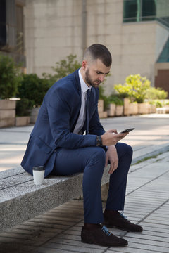 Young businessman looking at smart phone during coffee break