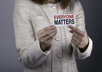 Everyone Matters. Businesswoman holding a card with a message te