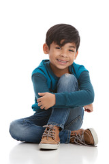 Full length portrait of a young mixed race boy sitting on the floor. Isolated on white.