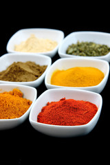 Colorful spice bowls on black background
