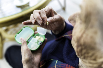 Elderly Turkish woman taking pills from medicine box
