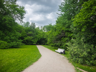 White bench near the road in city park in the summer before a thunderstorm