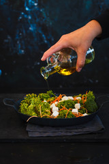 Detox and dieting salad. Hand pour olive oil on vegetarian salad.