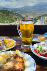 Potatoes with a piece of pork, Greek salad and glass of beer. Verandah Cafe on the pass with a view of the plateau of Lassithi. Crete