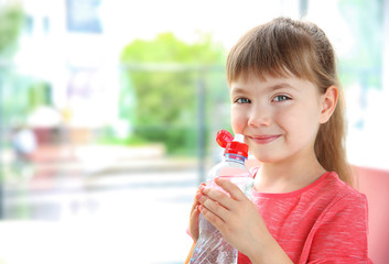 Beautiful small girl drinking water on kitchen