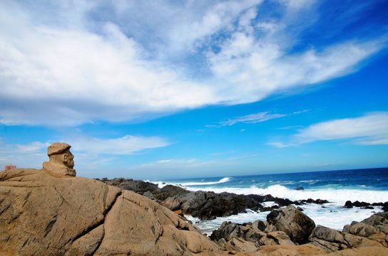 Beach in front of the house of Pablo Neruda, view onto the ocean, the head of Pablo Neruda made out of stone on a rock facing the sea