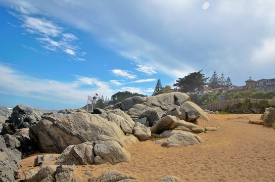 View onto the ocean outside of Pablo Nerudas house right at the beach with the house and green trees in the background