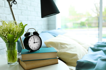 Lamp, books and flower bouquet on a side table