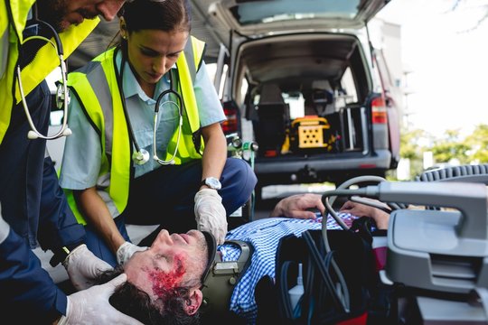 Emergency medical technicians healing injured man on road