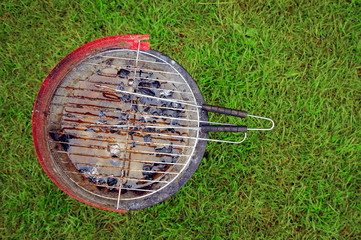 A used barbecue full of rain water on a camp site