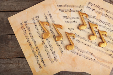 Naklejka premium Golden music notes and sheets on wooden table, top view