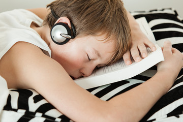 Boy with headphones asleep on top of textbook