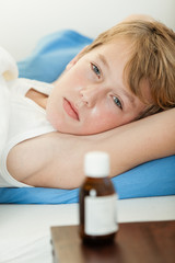 Sick boy laying down next to medicine bottle