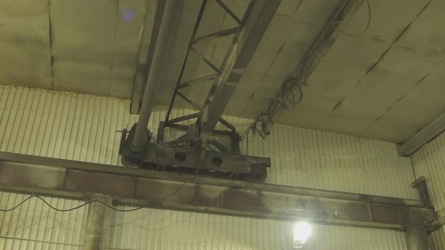 Electric hoist moves slowly under roof of plant.