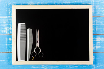 Blank blackboard and Hairdresser's scissors with comb on wooden