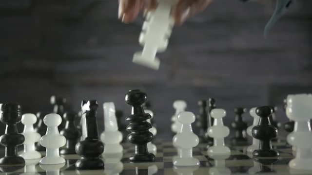 Hand of a player moves a chess piece on a board. 