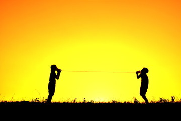 Silhouette children playing string phone at sky sunset