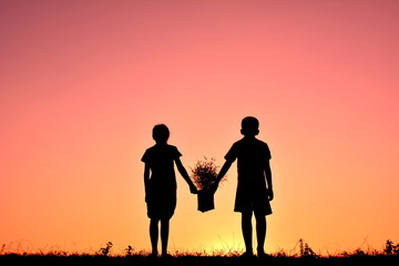 Silhouette children holding plant at sky sunset. Concept save world