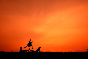Obraz na płótnie Canvas Silhouette of kids playing together at sunset