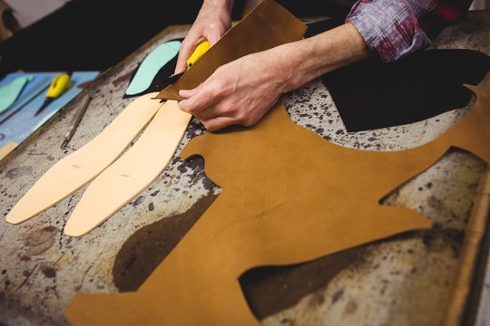 High angle view of cobbler cutting leather