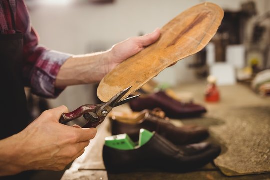 Close up of hands cutting the sole of a shoe