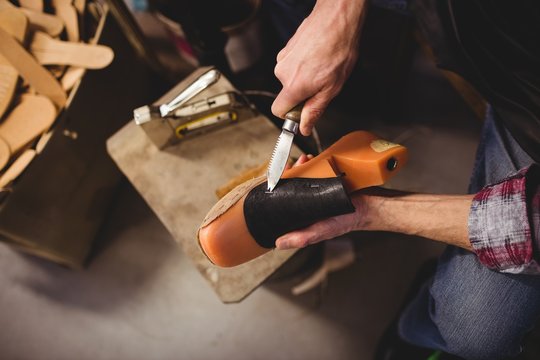 Overhead of cobbler using a knife on a shoe