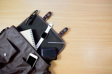Outfit of traveler. on wooden background: leather bag, smartwatch,smartphone, glasses, notebook and pen top view . retro style ,vintage tone