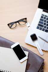 Business workplace from top smart watch, smart phone, glasses, laptop on wooden desk , retro style vintage tone
