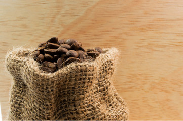 Coffee beans in hemp sack on wood background
