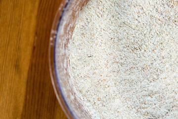 Whole-wheat flour in a bowl on wooden background