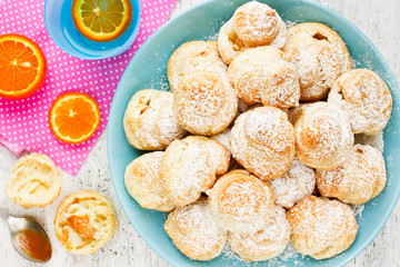 Sweet profiterole with cream, powdered sugar, fruit infused water