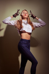 Blonde in black transparent gloves, shirt and jeans posing